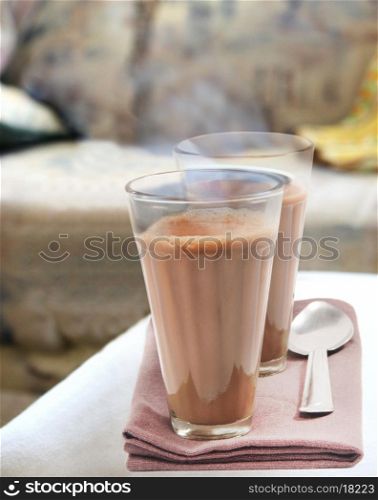 Glasses of morning chai with steel spoon kept on table napkin