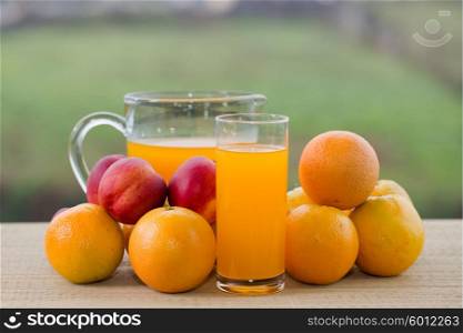 glasses of orange juice and peaches on wooden table outdoor