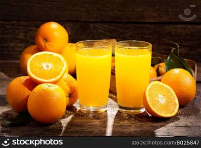 glasses of orange juice with fresh fruits on wooden background