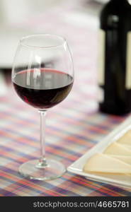 Glasses of red wine and cheese tray on a table with checkered tablecloth