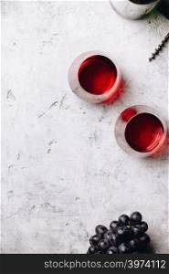Glasses of red wine and grapes on rustic concrete background, copyspace, flat lay