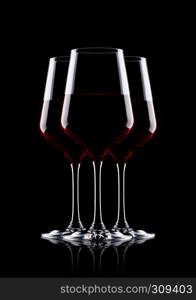 Glasses of red wine on black background with reflection
