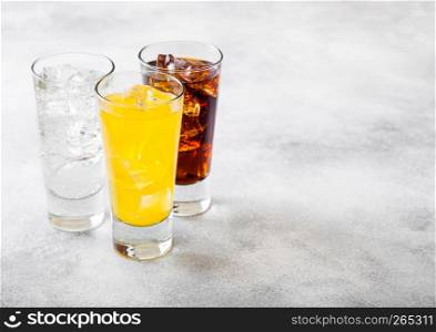 Glasses of soda drink with ice cubes and bubbles on stone kitchen background.