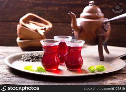 glasses of tea with teapot on wooden background