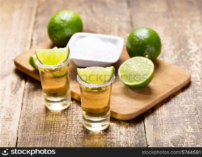glasses of tequila with lime on wooden table