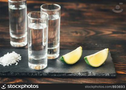 Glasses of tequila with lime wedges on the stone board