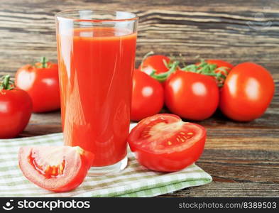 Glasses of tomato juice and fresh tomatoes on brown wooden table. tomato juice and fresh tomatoes on wooden table