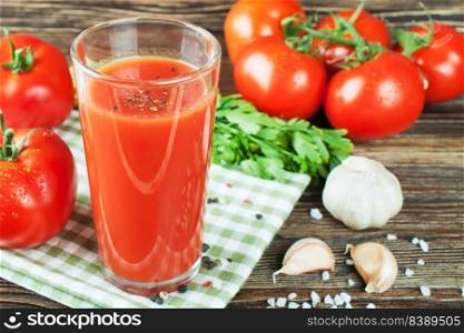Glasses of tomato juice and fresh tomatoes on brown wooden table. tomato juice and fresh tomatoes on wooden table
