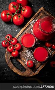 Glasses of tomato juice on a cutting board. On a black background. High quality photo. Glasses of tomato juice on a cutting board.