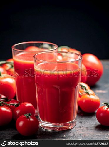 Glasses of tomato juice on the table. On a black background. High quality photo. Glasses of tomato juice on the table.