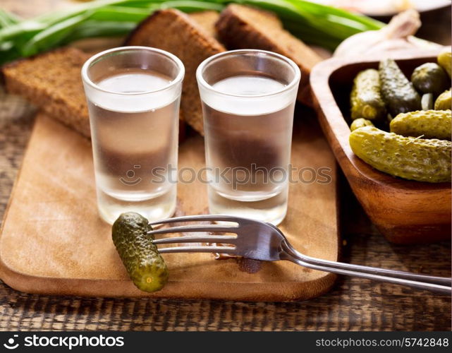 glasses of vodka with various snack on wooden table