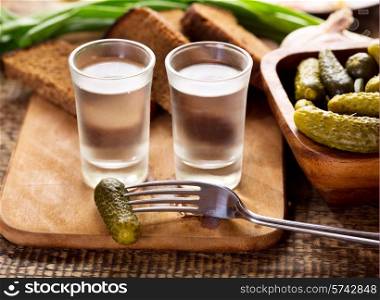 glasses of vodka with various snack on wooden table