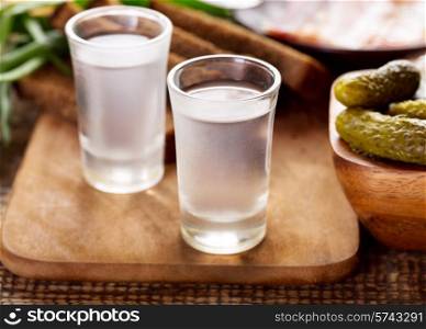 glasses of vodka with various snack on wooden table
