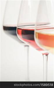 Glasses of white, red and rose wine over white background