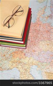 glasses on pile of books on map of europe
