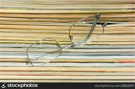 glasses on the background of the stack of magazines