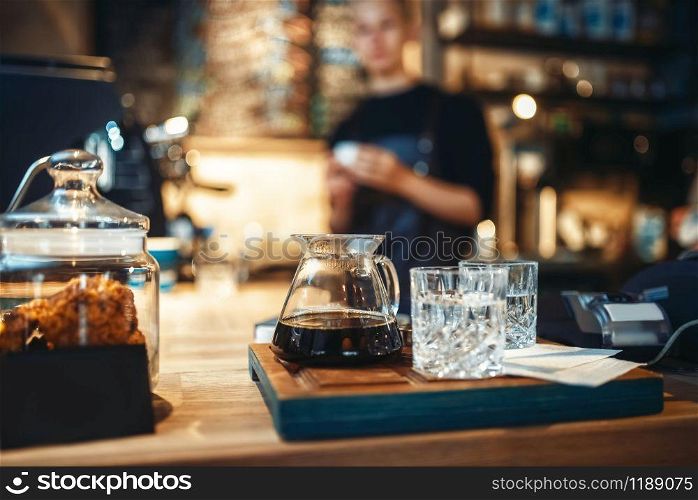Glasses with black coffee and filtered water, male barista at cafe or bar counter on background. Professional espresso preparation by bartender in cafeteria, barman occupation. Glasses with black coffee and filtered water