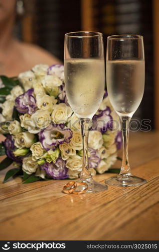 Glasses with champagne and a bouquet on a table.