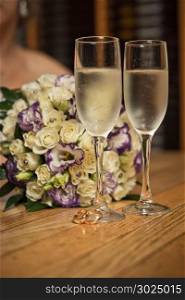 Glasses with champagne and a bouquet on a table.
