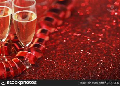 Glasses with Champagne and gifts on red glitters background