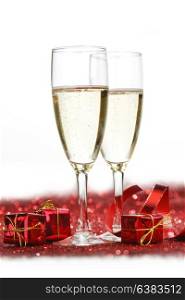 Glasses with Champagne and gifts on red glitters isolated on white background