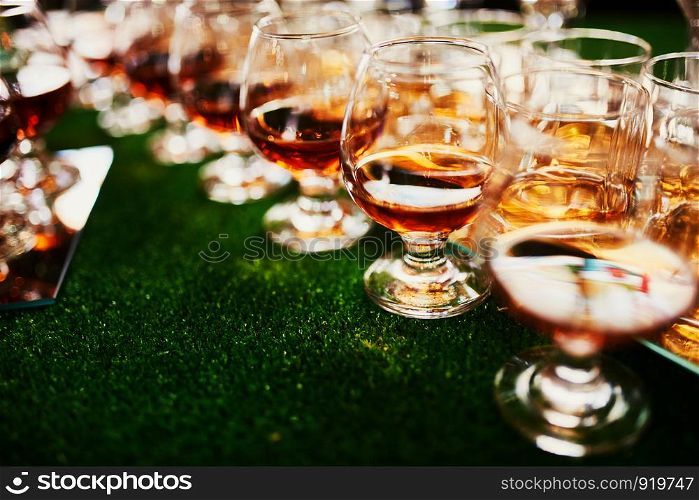 glasses with cognac, whiskey stand on the bar. a lot of glasses with cognac. alcohol in the glasses. Various alcohol drinks standing on bar. glasses with cognac on the bar