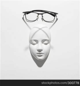 Glasses with plaster mask face for reading and person with visual impairment, long shadows on a white background, copy space. Top view.. Gypsum face sculpture with elegant glasses with long crossing shadows on a white background, copy space. Top view.