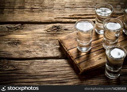 Glasses with vodka on the old Board. On wooden background.. Glasses with vodka on the old Board.