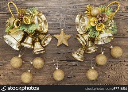 Glittering gold Christmas balls, bells, and star on wooden background