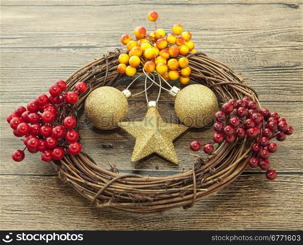 Glittering gold Christmas balls, bells,wreath, and star on wooden background with snow