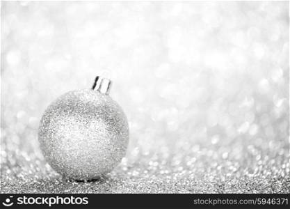 Glittering silver Christmas ball with in shiny glitters background