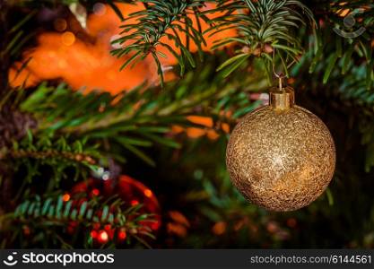 Glittering Xmas bauble in gold hanging on a tree