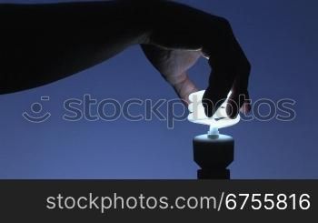 Glnhbirne wird gegen Energiesparlampe ausgetauscht, blauer Hintergrund