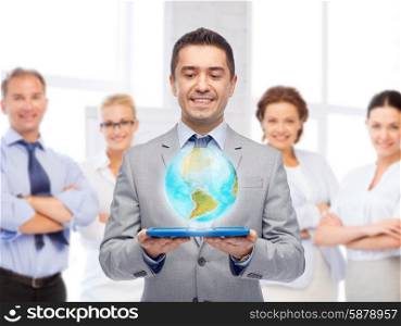 global business, people and technology concept - happy smiling businessman in suit holding tablet pc computer with virtual globe projection over group of people and office room background