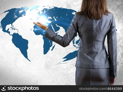 Global interaction. Rear view of businesswoman pointing at world map