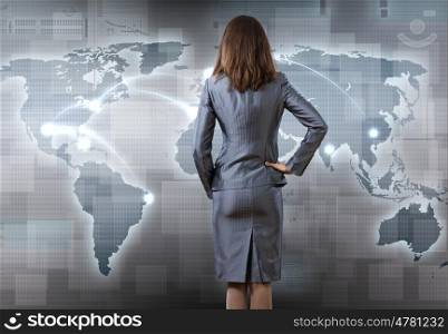 Global interaction. Rear view of businesswoman pointing at world map