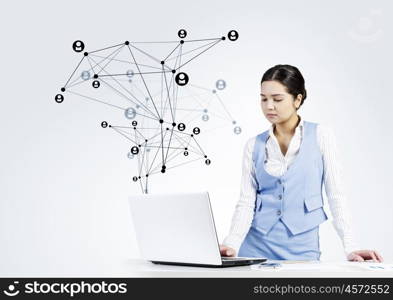 Global network interaction. Beautiful young lady at desk working on laptop with social network concept at background