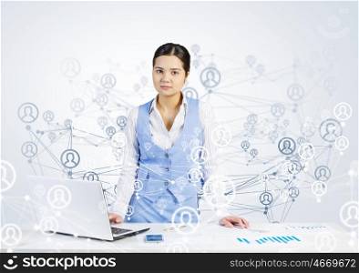Global network interaction. Beautiful young lady at desk working on laptop with social network concept at background