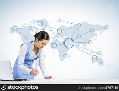 Global network interaction. Beautiful young lady at desk working on laptop with social network concept