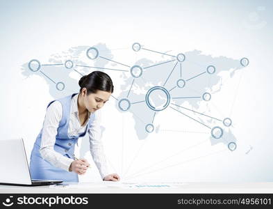 Global network interaction. Beautiful young lady at desk working on laptop with social network concept