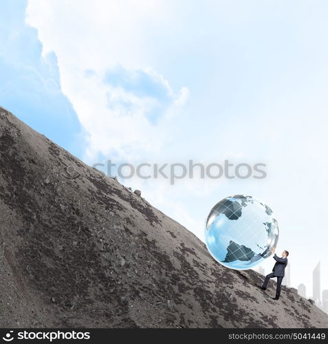 Global technologies. Young businessman rolling Earth planet up th hill