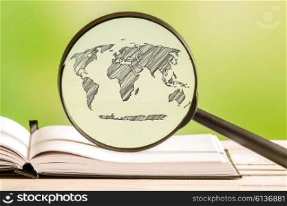 Global world with a pencil drawing of a world map in a magnifying glass