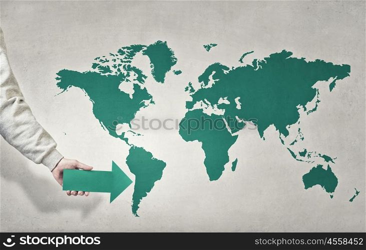 Globalization concept. Close up of hand pointing with arrow at world map