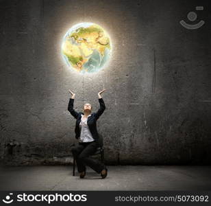 Globalization concept. Image of businesswoman holding earth planet in hands above head. Elements of this image are furnished by NASA