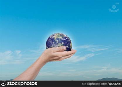 Globe, earth in human hands over blue sky background. Idea for save the world. Elements of this image furnished by NASA