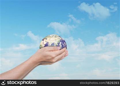 Globe, earth in human hands over blue sky background. Idea for save the world. Elements of this image furnished by NASA