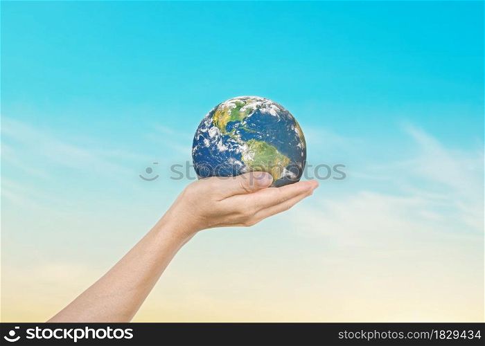 Globe in hands over blue sky background. Save of earth. Elements of this image furnished by NASA