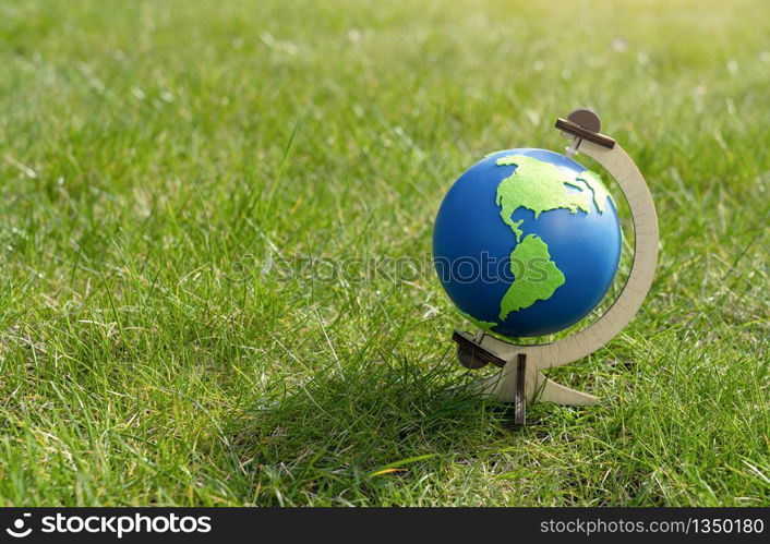 Globe of the planet Earth standing on green grass in sunny day on spring or summer, Eco symbol, Green map on blue globe on lawn in the garden with copy space, Concept - Earth Day on 22, April