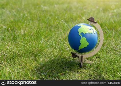 Globe of the planet Earth standing on green grass in sunny day on spring or summer, Eco symbol, Green map on blue globe on lawn in the garden with copy space, Concept - Earth Day on 22, April
