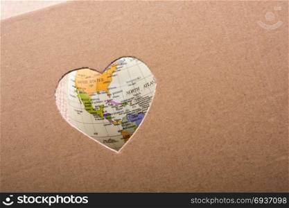 Globe seen through the heart shape hole on paper